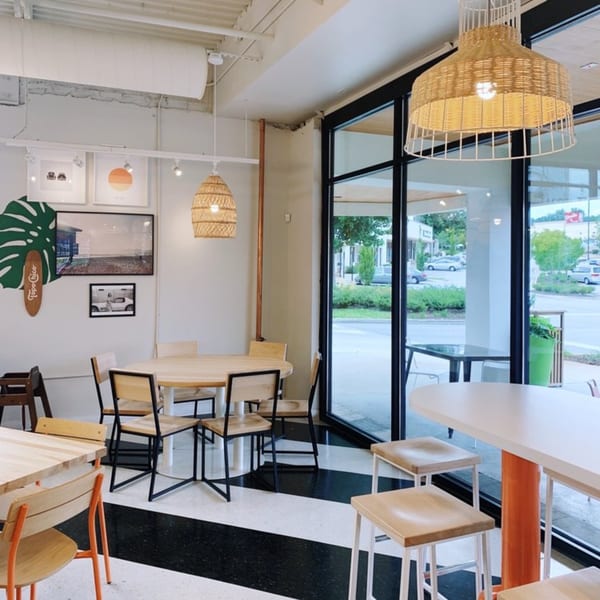 Bright, modern Yumbii dining room with light wood tables, black and white checkered floor, and large windows.