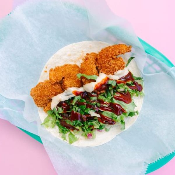 Yumbii's crispy chicken taco with lettuce, white sauce, and dark red sauce on a tortilla.